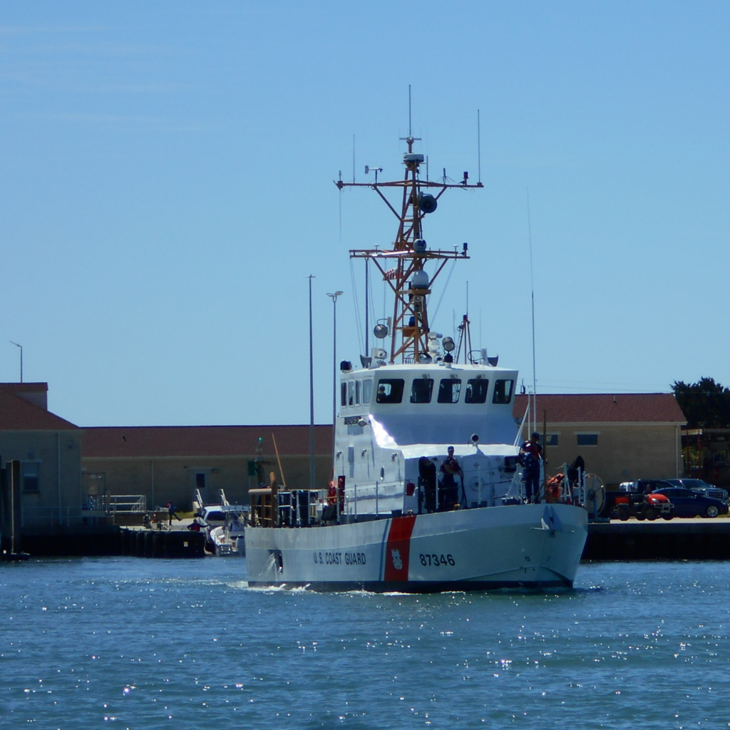 Coast Guard Ship leaving port near field work area. 