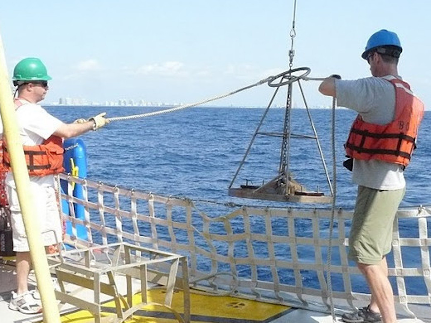 Field team members raising equipment out of ocean during field work.