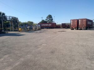 Industrial area with white pipes on the left side and powerlines in background.